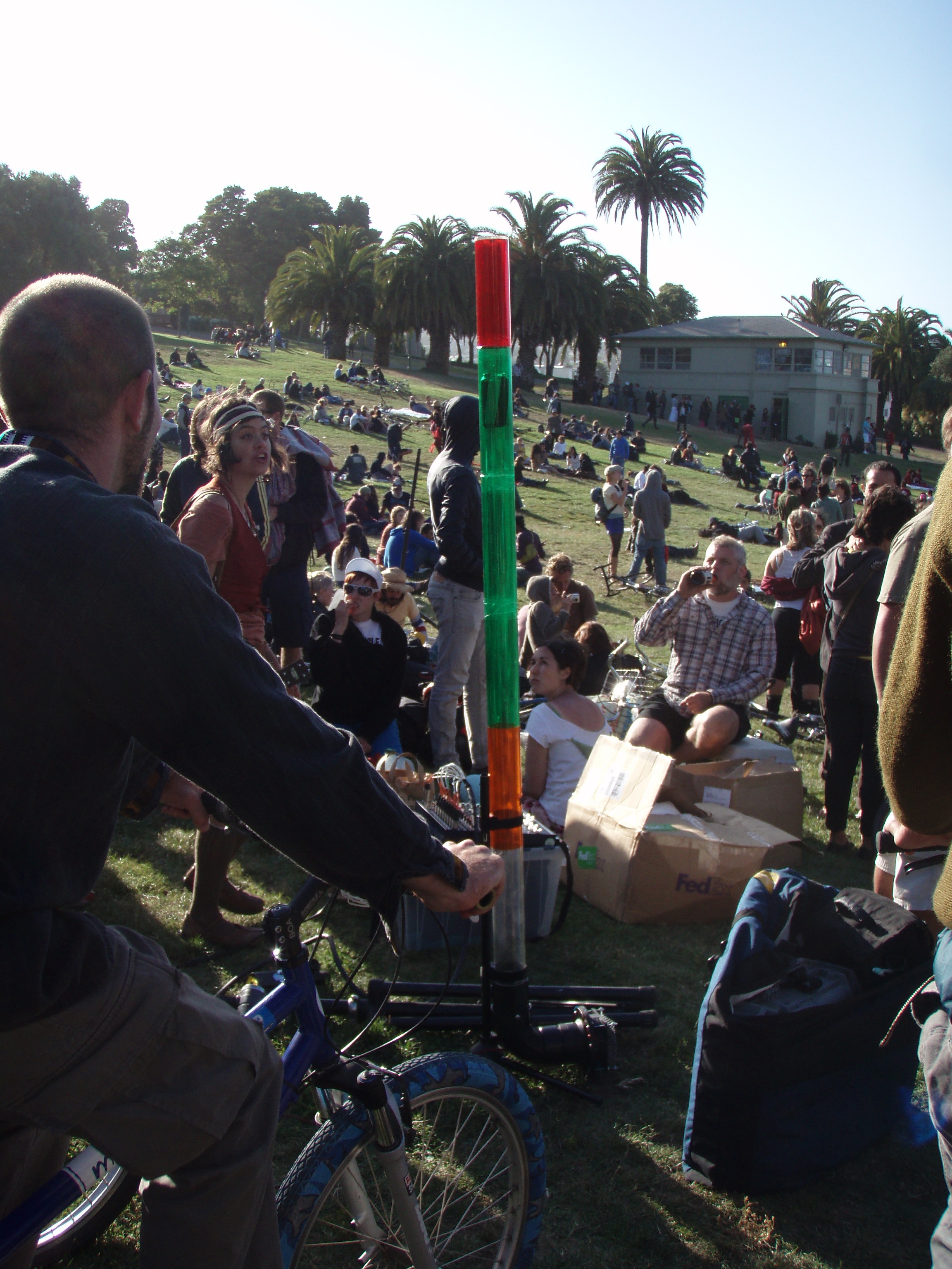 After everyone confused this object with a bong, it was revealed to be the power meter.  There was a fan at the bottom of the tube whose speed was regulated by the power being generated by the cyclists.  As they pedaled, an empty beer can would move up and down the tube--into the red if they pedaled too much and into the yellow if they were not pedaling enough.